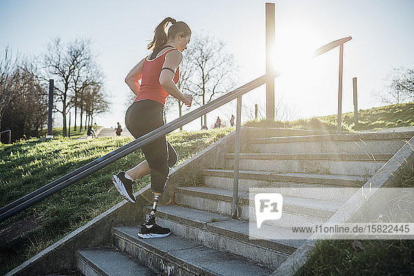 Sportliche junge Frau mit Beinprothese beim Treppensteigen
