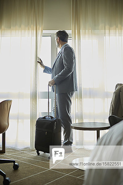 Geschäftsmann im Hotelzimmer der aus dem Fenster schaut