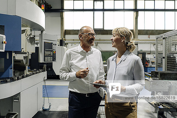 Man and woman with tablet talking in a factory