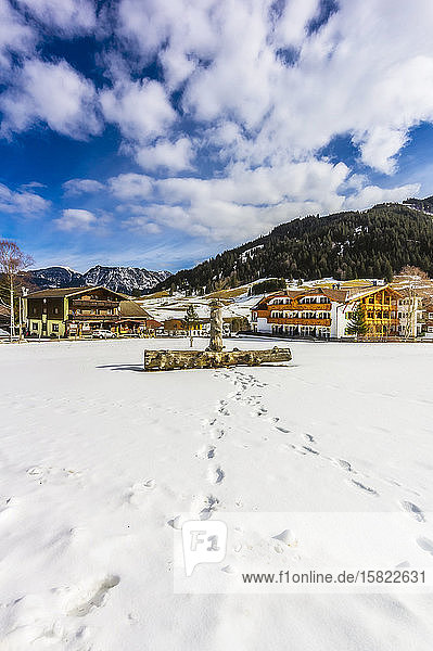 Österreich  Tirol  Tannheim  Fussspuren  die zu einem Holzscheit führen  der im Schnee vor Stadthäusern liegt
