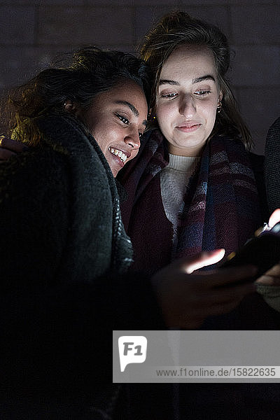 Freunde betrachten beleuchtete Smartphones im Dunkeln