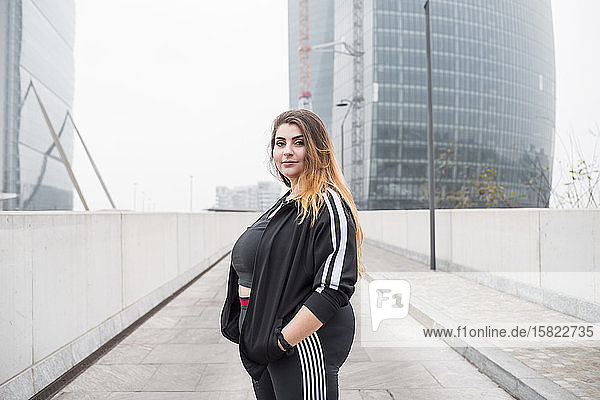 Sportliche junge Frau in Übergröße  die in der Stadt posiert