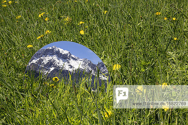 Round mirroe lying in grass reflecting the mountains of Val Badia Alto Adige Ilaty