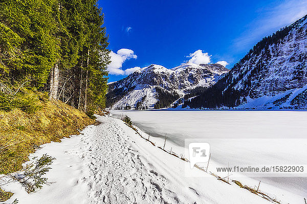 Austria  Tyrol  Tannheim  Snowy footpath stretching along shore of frozen Vilsalpsee lake