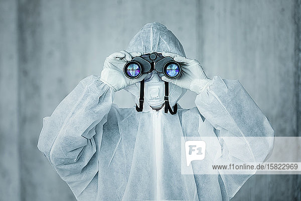 Mann in Schutzkleidung schaut durch ein Fernglas