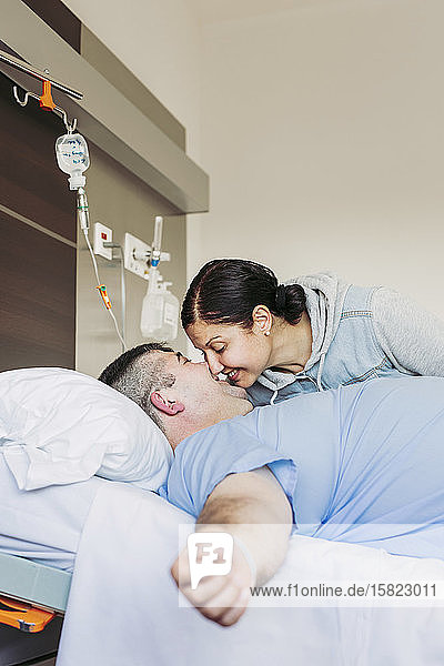 Liebevolle Frau besucht Ehemann im Krankenhausbett liegend