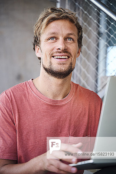 Portrait eines jungen Mannes mit T-Shirt und Laptop