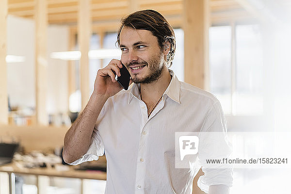 Businessman on the phone in wooden open-plan office