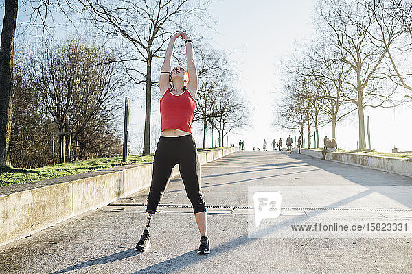 Sportliche junge Frau mit Beinprothese  die ihre Arme hebt