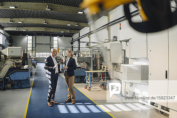 Businessman and businesswoman talking in a factory