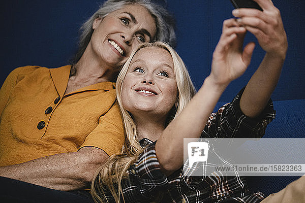 Glückliche Mutter und erwachsene Tochter  die auf der Couch ein Selfie machen