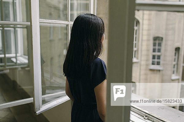 Back view of woman looking out of window