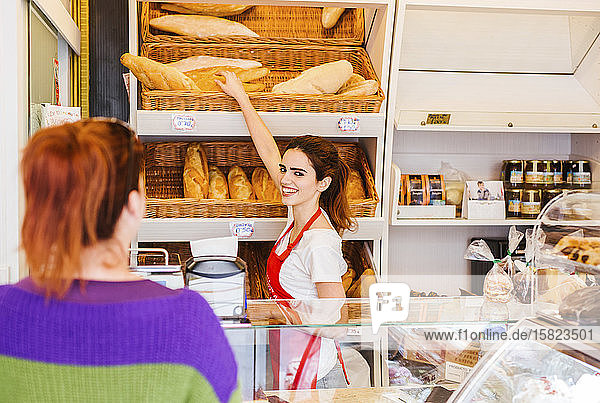 Junge Frau bedient weibliche Kundin in einer Bäckerei