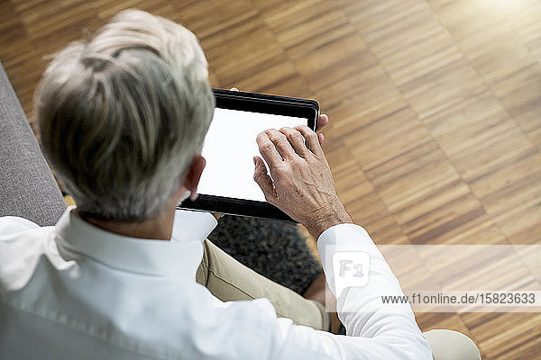 Älterer Mann benutzt Tablette zu Hause