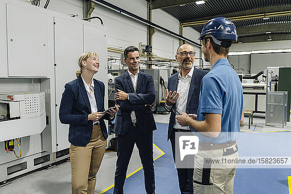 Business people and worker talking in a factory