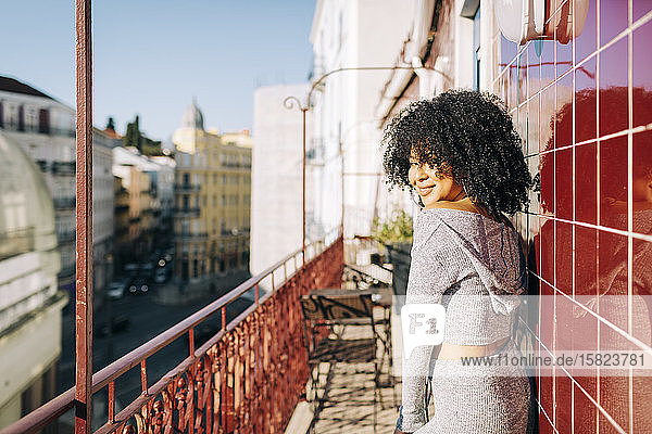 Porträt einer jungen Frau mit lockigem Haar auf dem Balkon
