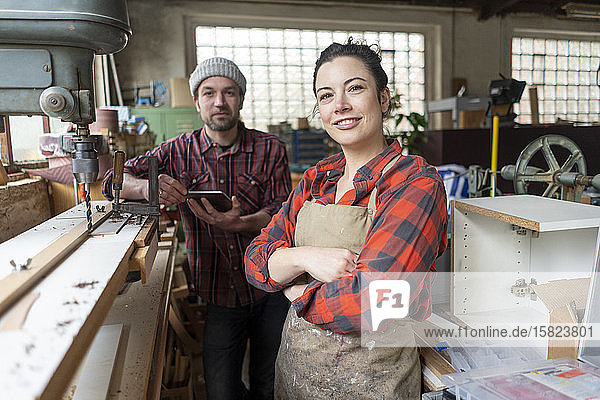 Porträt einer selbstbewussten Handwerkerin und eines Handwerkers in ihrer Werkstatt