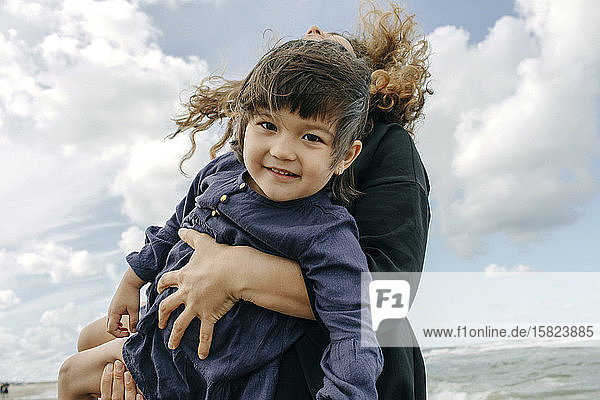 Portrait of happy little girl on her mother's arms