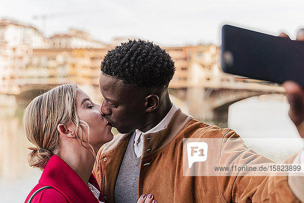Affectionate young couple kissing and taking a selfie in the city of Florence  Italy