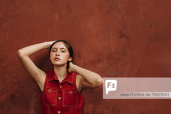 Porträt eines weiblichen Teenagers in rotem Trägerkleid vor einer Wand