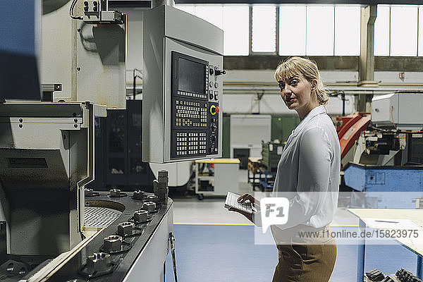 Porträt einer selbstbewussten Geschäftsfrau mit drahtloser Tastatur in einer Fabrik