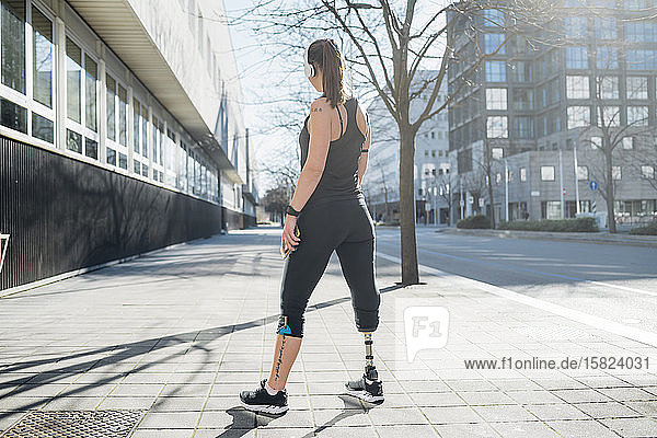 Sportliche junge Frau mit Beinprothese steht in der Stadt