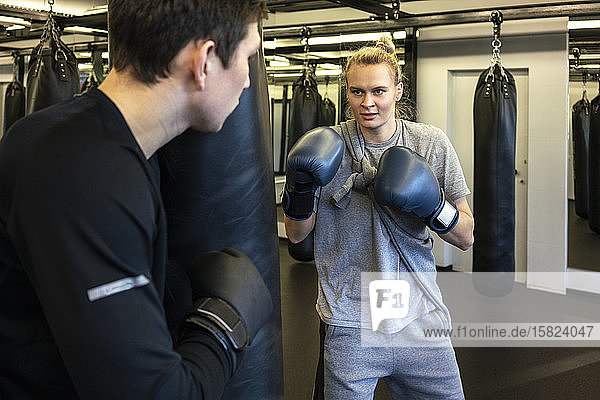Trainerin und Boxerin beim Sandsacktraining im Fitnessstudio