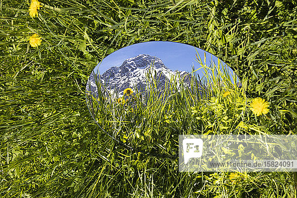 Round mirroe lying in grass reflecting the mountains of Val Badia Alto Adige Ilaty