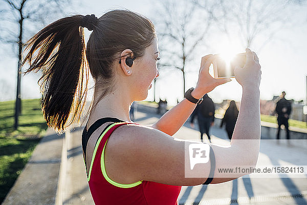 Sportliche junge Frau mit kabellosen Kopfhörern  die ein Selfie