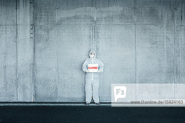 Mann in Schutzkleidung mit einem Geschlossen -Schild