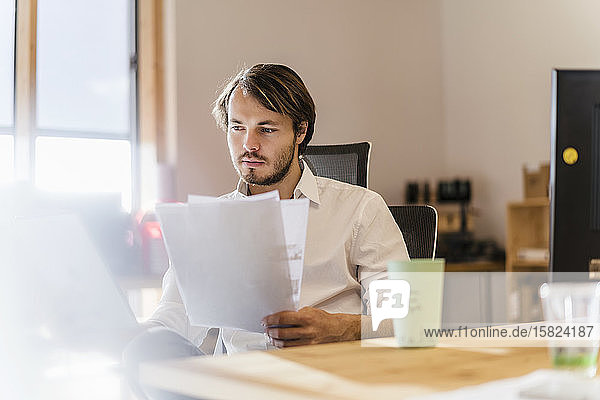 Businessman reading document at desk in office
