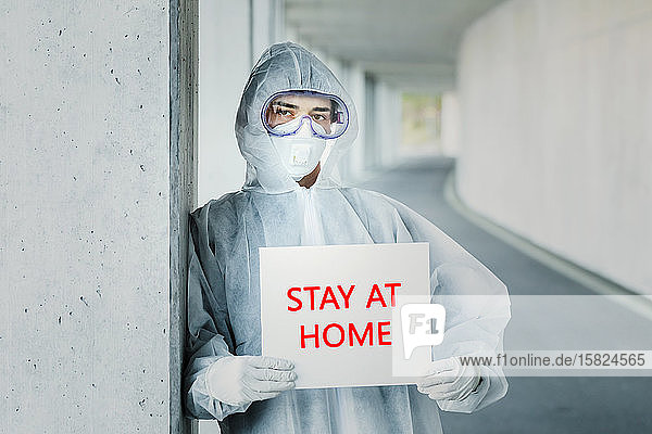 Porträt eines Mannes in Schutzkleidung mit einem Bleiben Sie zu Hause -Schild