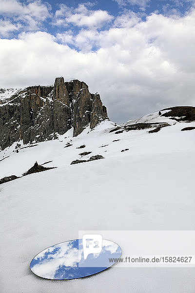 Mirror lying in snow reflecting the sky at the Sella group in winter Dolomites Alto Adige Italy