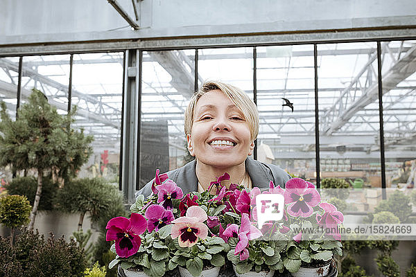 Smiling woman with pansies in flower shop
