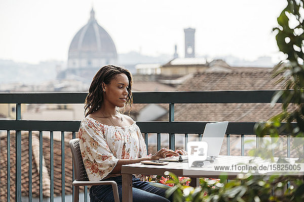 Junge Frau mit Laptop auf einem Balkon in Florenz  Italien
