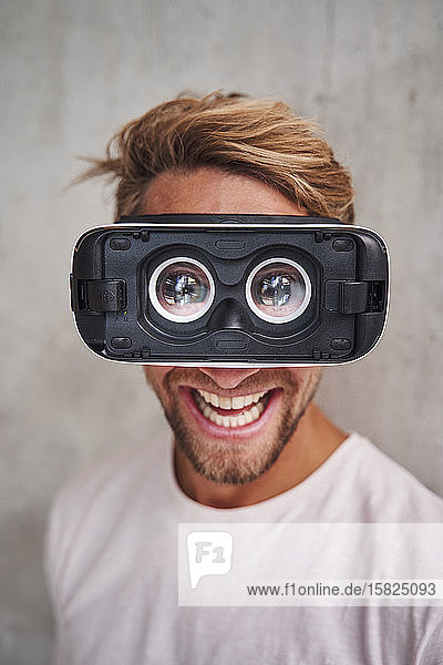 Laughing young man wearing virtual reality goggles