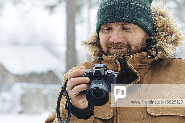 Portrait of smiling man looking at digital camera in winter