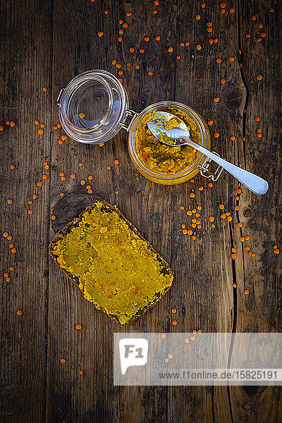Glas mit hausgemachter roter Linsenpaste und Scheibe Vollkornbrot