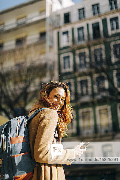 Portrait of happy young woman with backpack in the city  Lisbon  Portugal