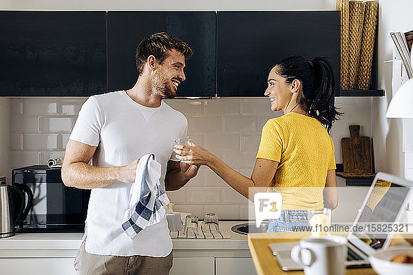 Glückliches junges Paar beim gemeinsamen Abwasch in der Küche zu Hause