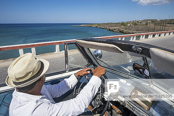 Taxifahrer mit einem Oldtimer-Cabriolet an der Küste Kubas