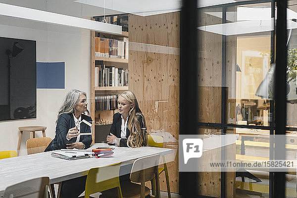 Reife und junge Geschäftsfrau untersucht Architekturmodell im Loft-Büro