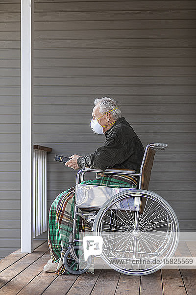 Senior man in wheelchair wearing protective mask to preventÂ coronavirusÂ transmission on porch