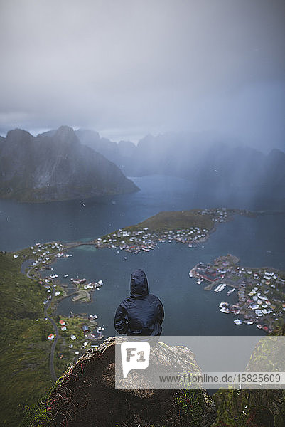 Norwegen  Lofoten  Reine  Mann blickt vom Reinebringen-Berg bei Regen auf den Fjord
