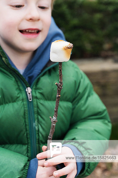 Junge beobachtet gerösteten Marshmallow am Stiel