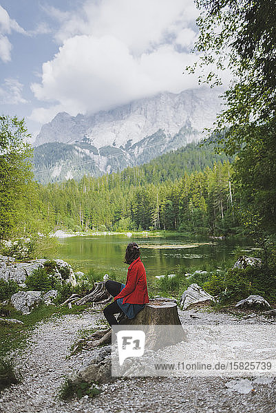 Germany  Bavaria  Eibsee  Woman sitting by Frillensee lake