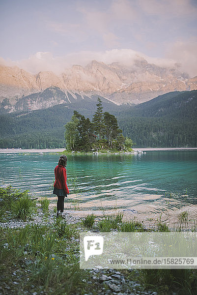 Germany  Bavaria  Eibsee  Young woman standing at shore ofÂ EibseeÂ lake in Bavarian Alps
