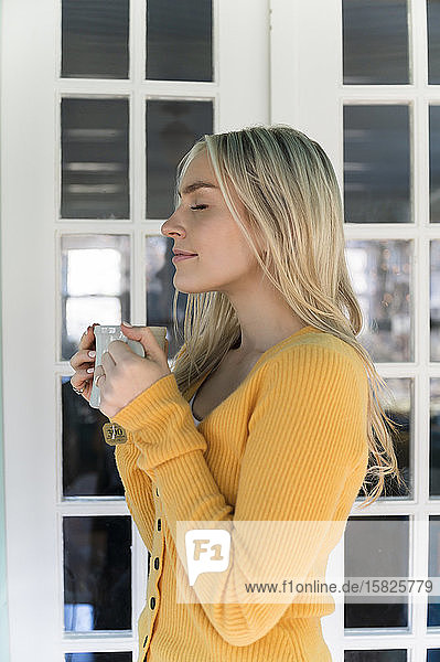 Portrait of woman in yellow sweater holding mug