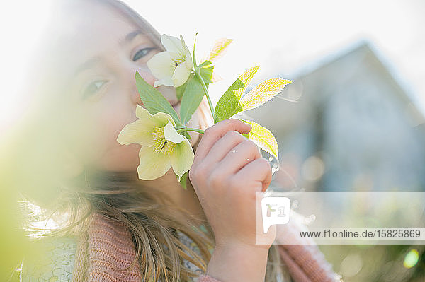 Porträt eines an gelben Blumen riechenden Mädchens