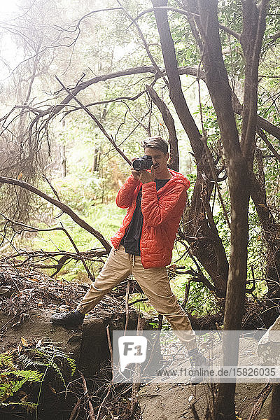 Ein junger Mann fotografiert in einem Regenwald